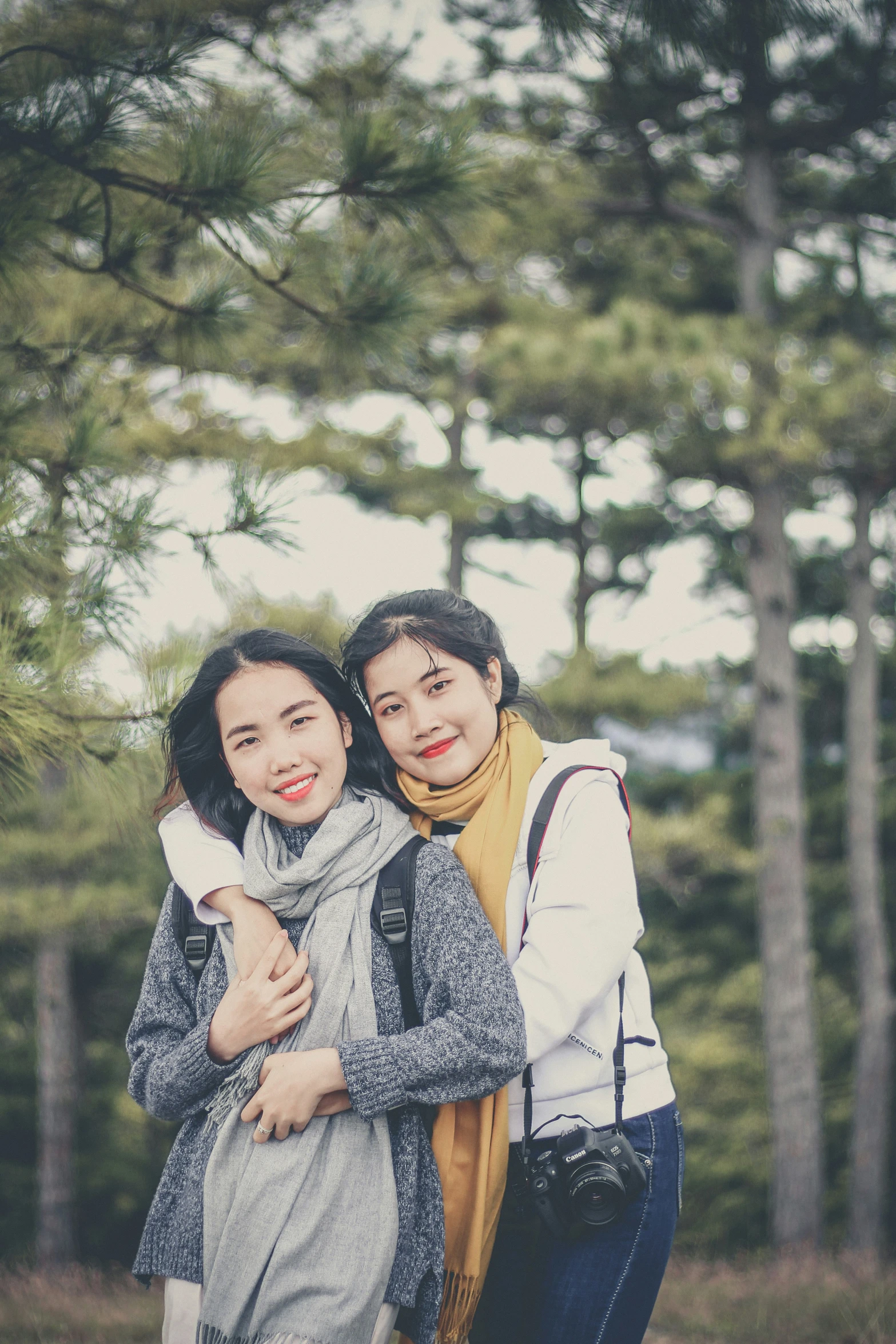 two people standing together near a forest