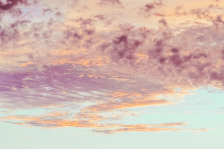 a hazy sky with lots of pink clouds and blue skies