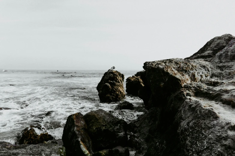 a lighthouse on the edge of the ocean surrounded by rocks