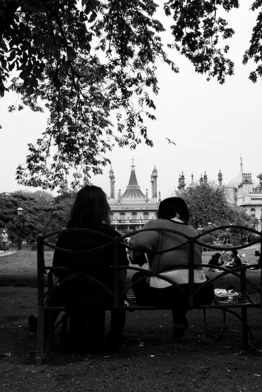 a couple sits on a bench while the city skyline is in the background