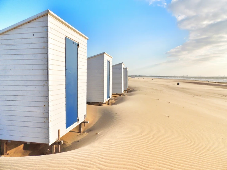 a row of white beach huts along the shore