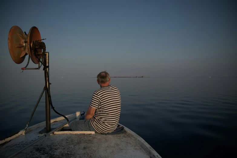 a man sitting in the bow of a boat on top of water