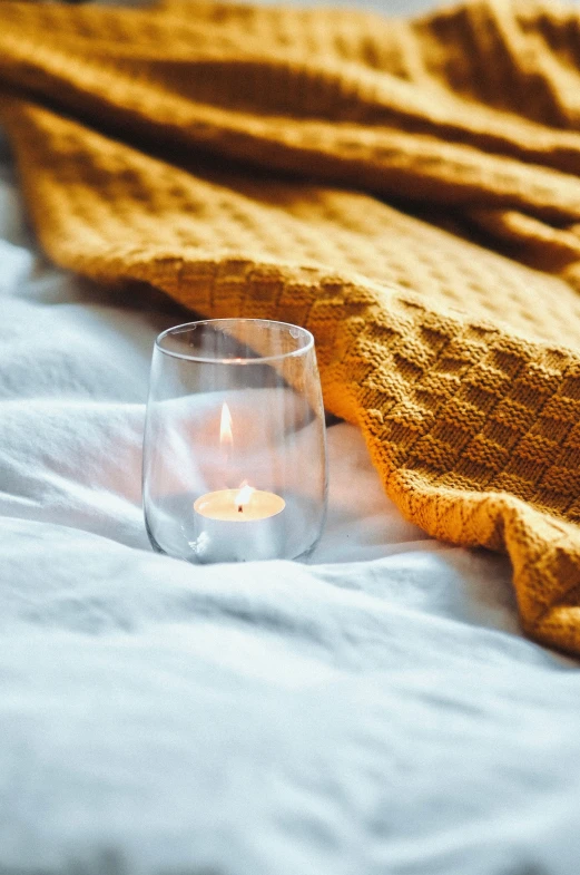 a close up of a lit candle near some blankets