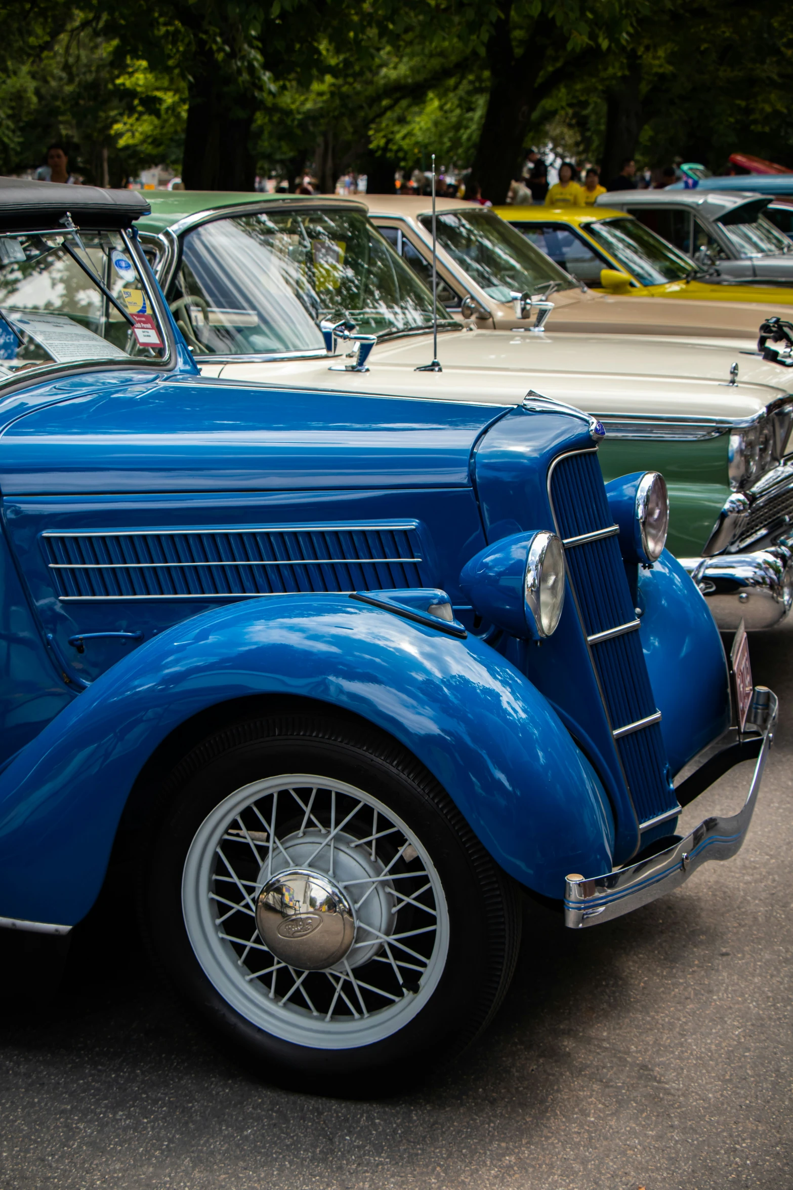 an old blue car is parked in front of others