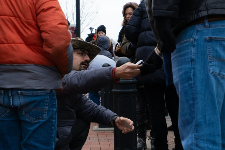 a child holds up a cell phone as people line up on the side walk