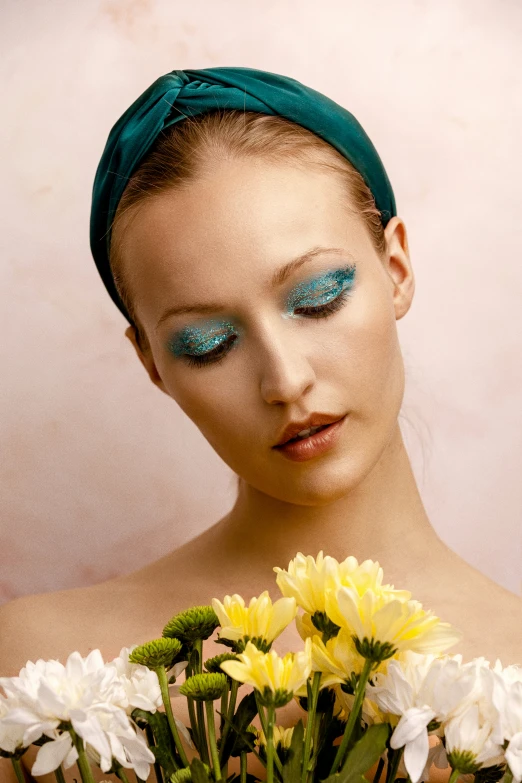 the young woman is wearing bright makeup and holding flowers