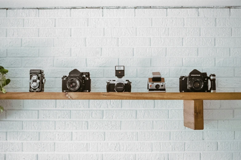 six old cameras on top of a wooden shelf