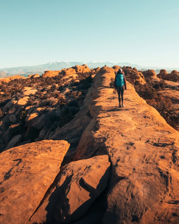 a man with blue jacket on a hill with large rocks