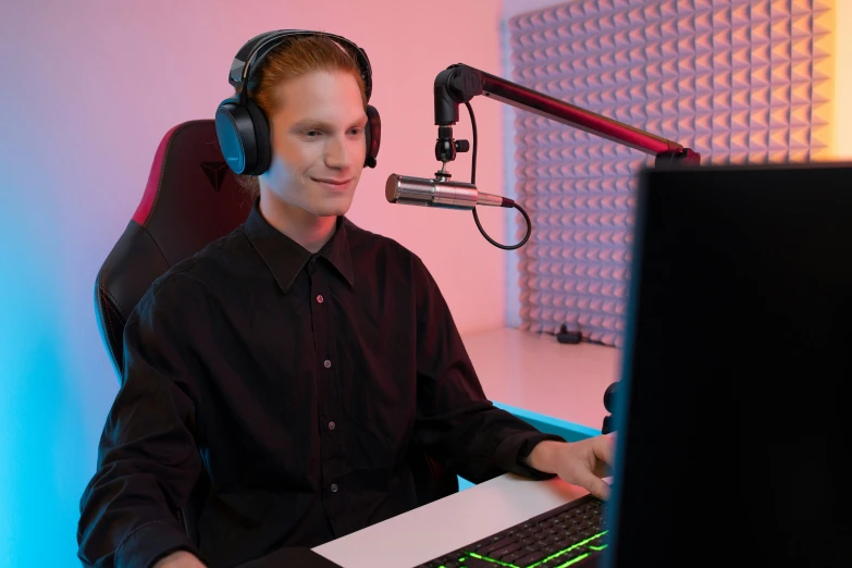 a man is sitting in front of a computer and talking on a microphone