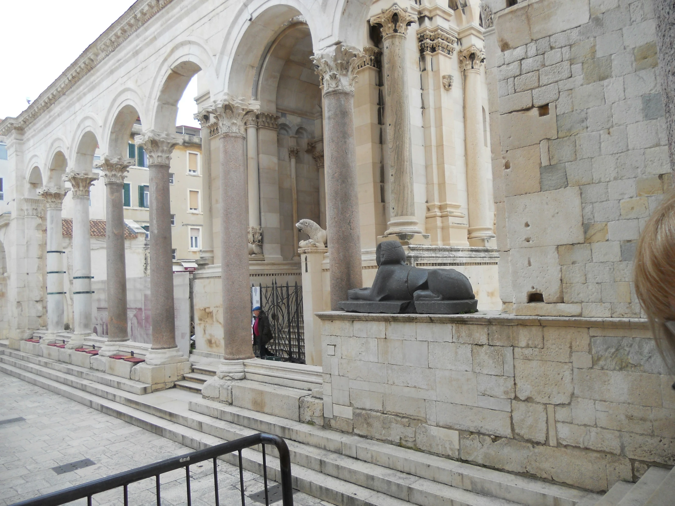 the statue in the courtyard is outside by stone columns