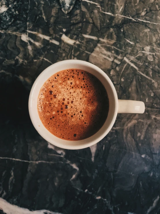 a coffee cup filled with chocolate sitting on top of a marble table