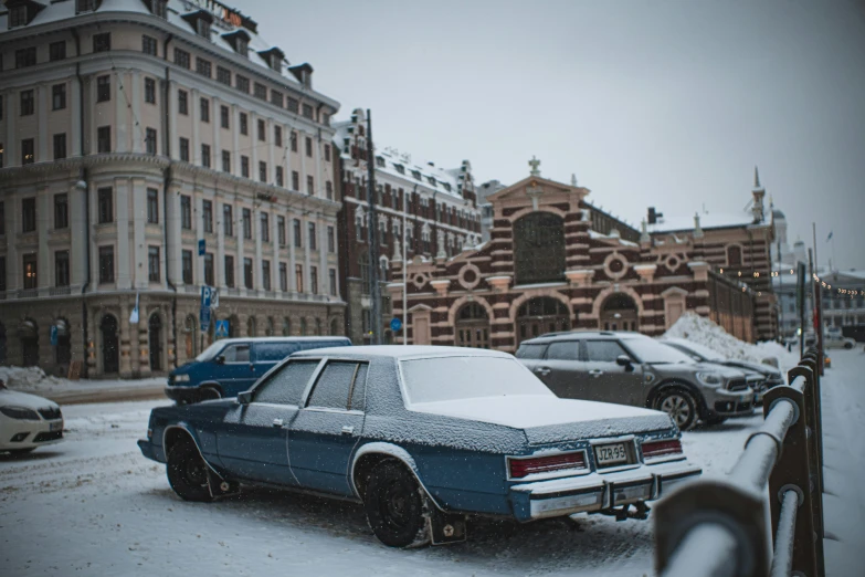 some very pretty cars parked by the road in the snow