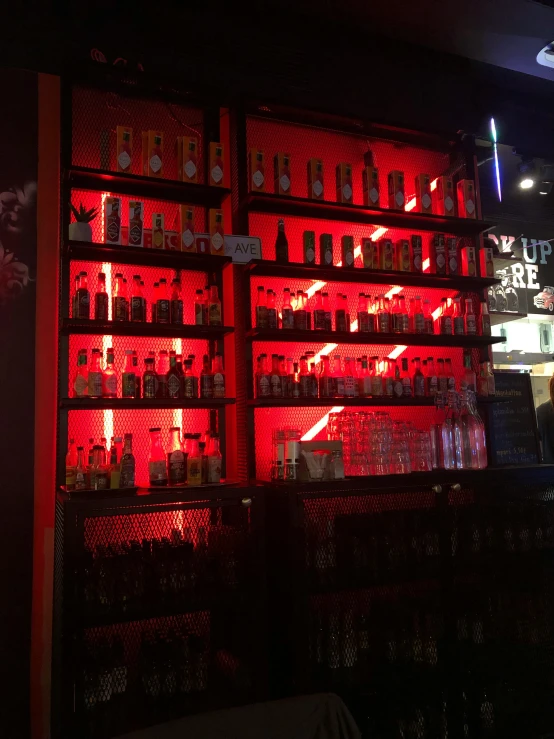 a dimly lit bar with beer bottles on red lights