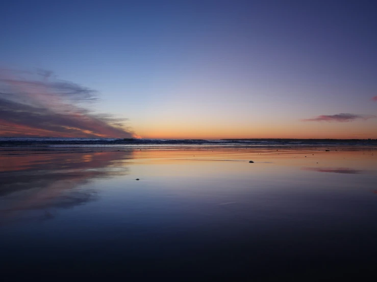 the sky is setting at the beach and it is almost empty