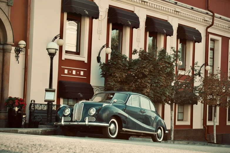 an old, black car sits parked in front of a building