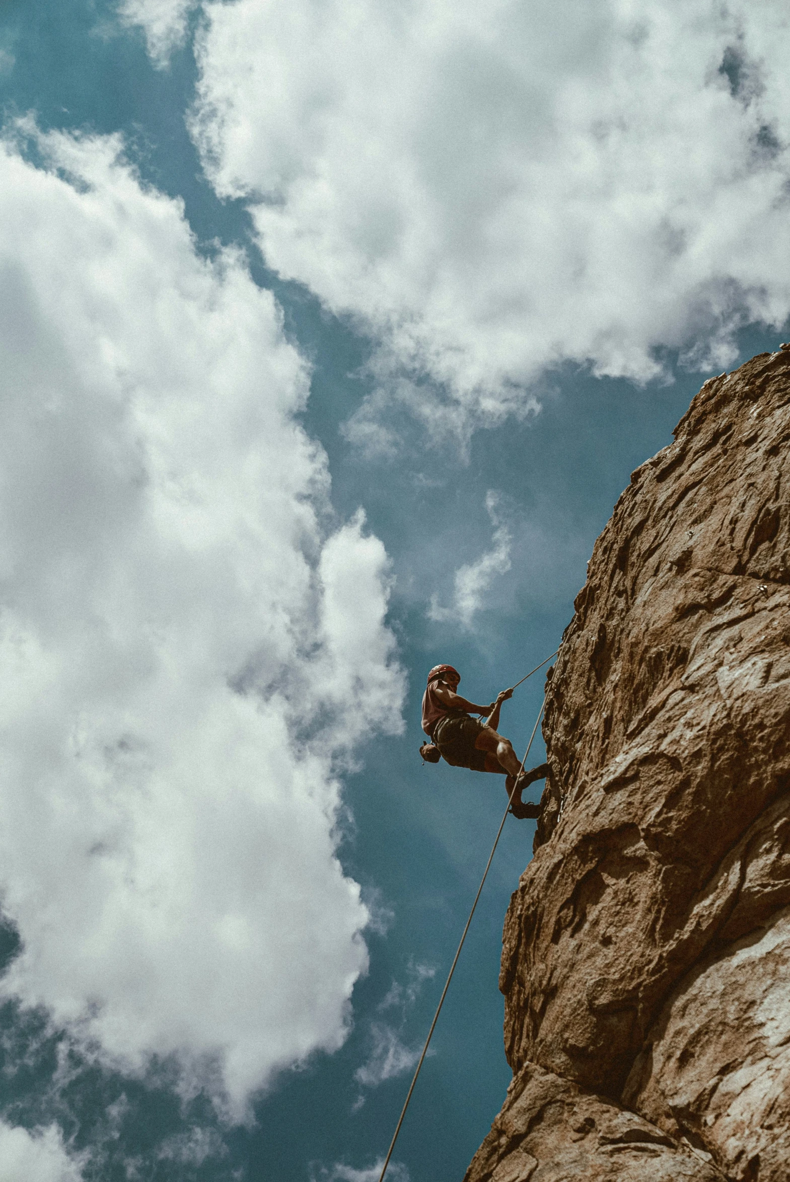 a man in a helmet climbing down a mountain