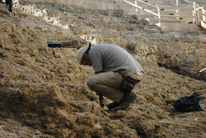 a man digging in some grass by an old concrete staircase