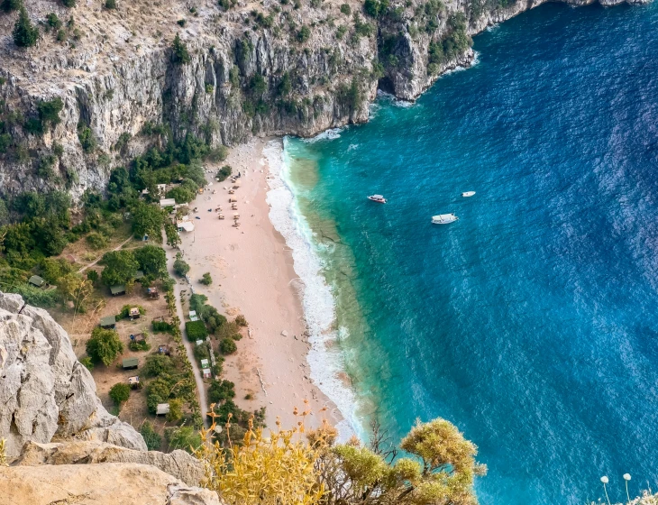 people walking and sailing on a sandy beach near the ocean