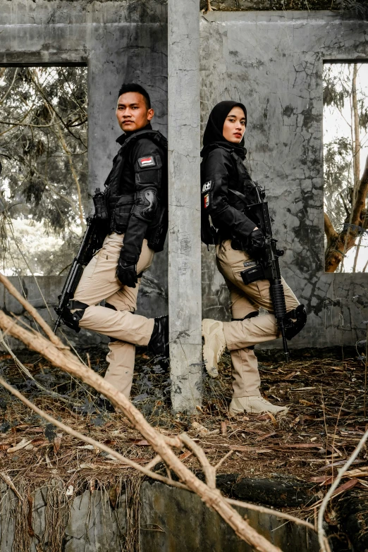 two people in full gear walk past a destroyed building