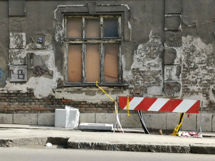 a broken down wall with two windows and barricade signs