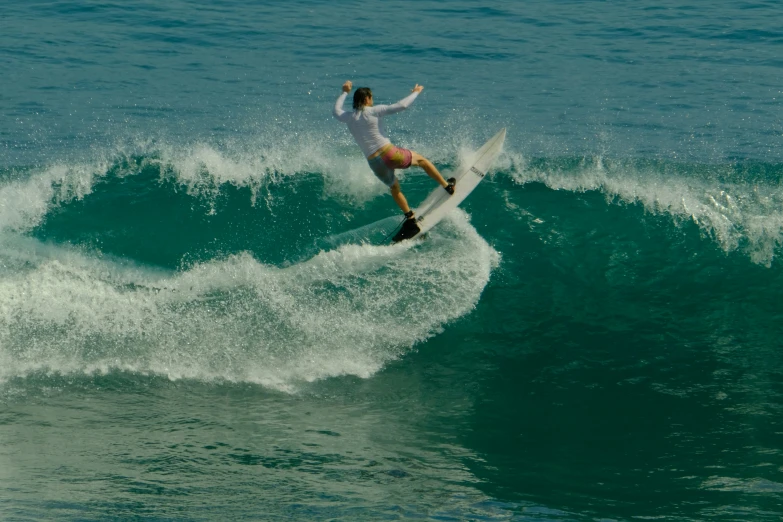 a woman in shorts riding a wave on top of a surfboard