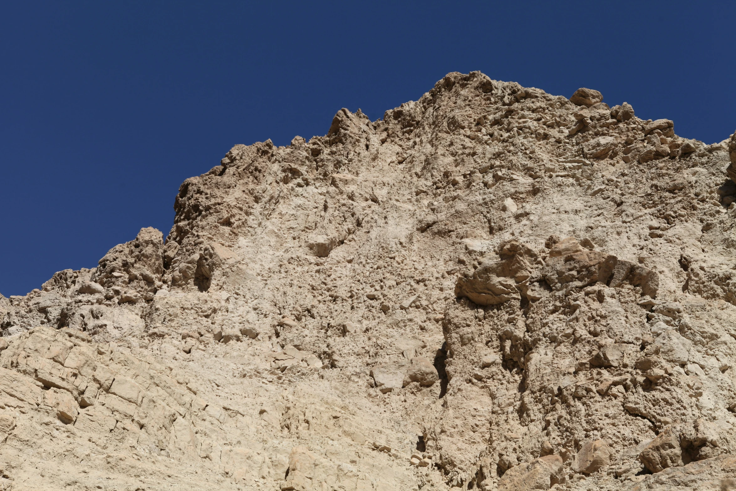 a big rock face sitting on top of a sandy hill