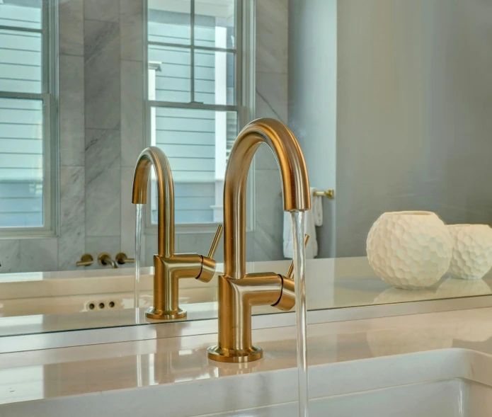 gold faucet with marble sink and windows