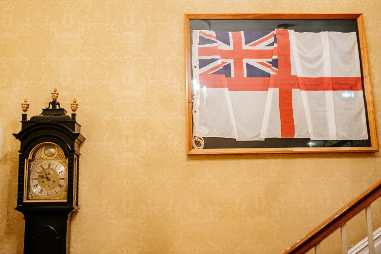 there is a small clock in a corner with a flag hanging on the wall