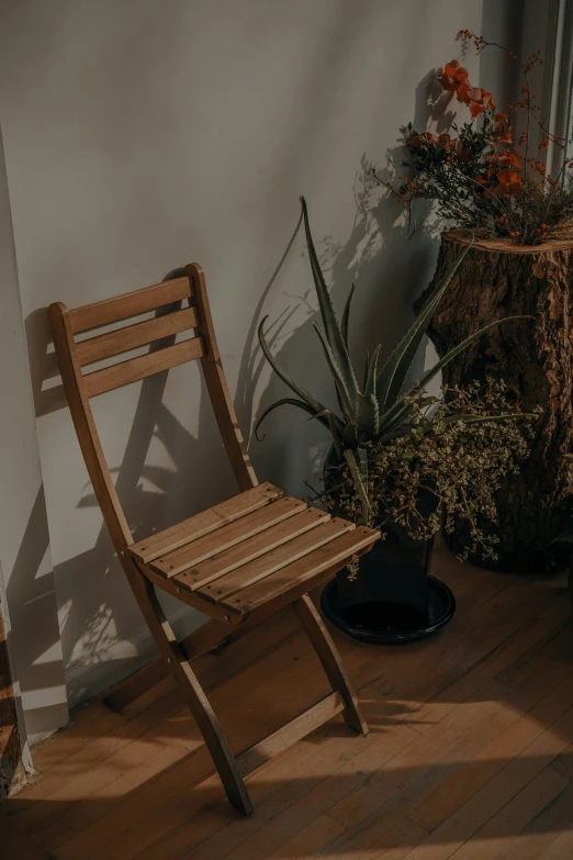 a wooden chair sitting on the floor next to a plant