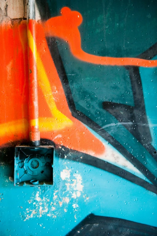 a square object stands against a wall with graffiti