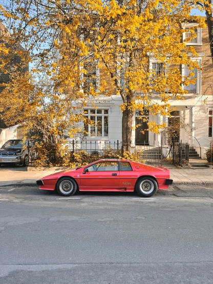 a red sports car is parked along the street in front of a house