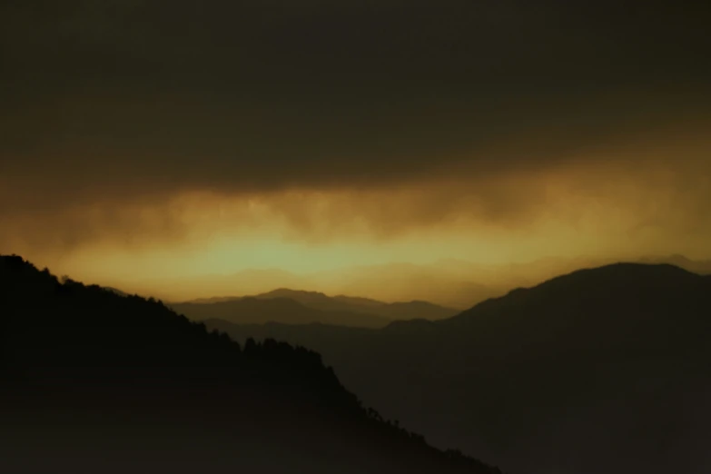 the sky over mountains and clouds is illuminated by yellow light