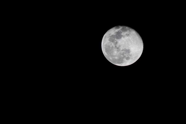 the moon rises above the black sky during the day