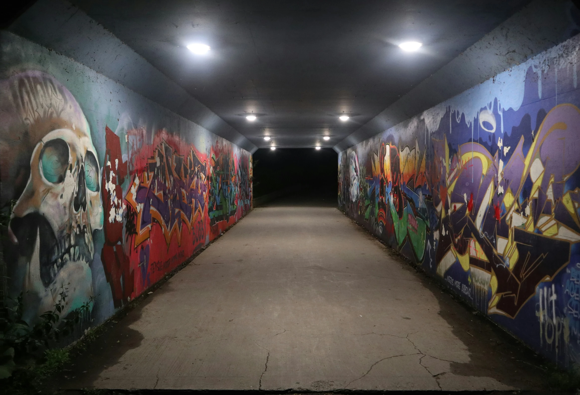 a concrete walkway with colorful graffiti on the walls