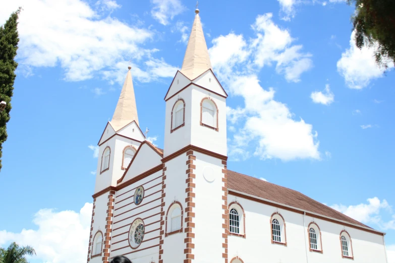 an old, brick church with two towers under a partly cloudy sky