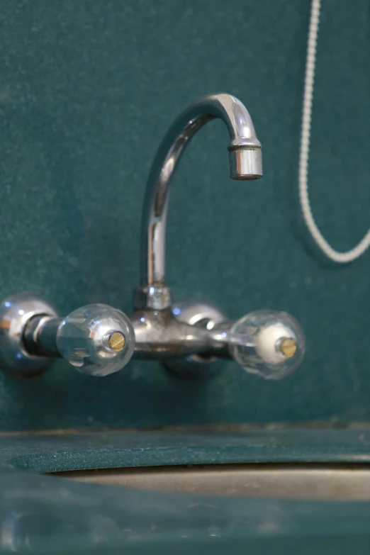 a chrome sink with three small balls at the faucet