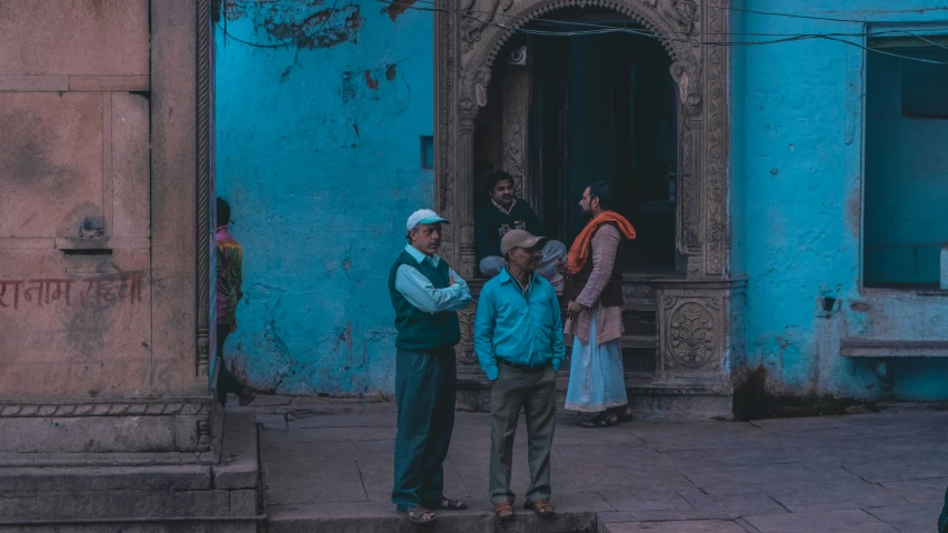 several people standing in front of a blue building