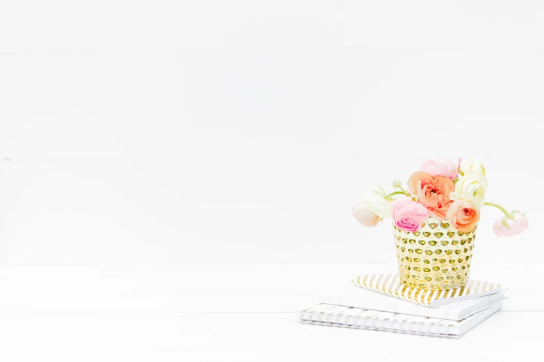 a gold vase filled with flowers sitting on top of a table