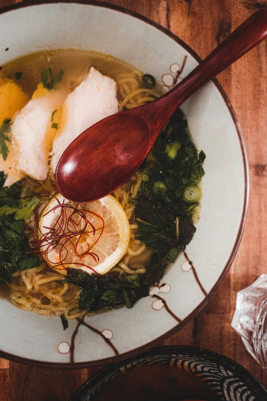 a red spoon is in a bowl with soup