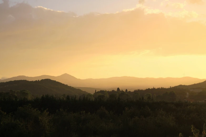 a sunset in the mountains with a bird flying above