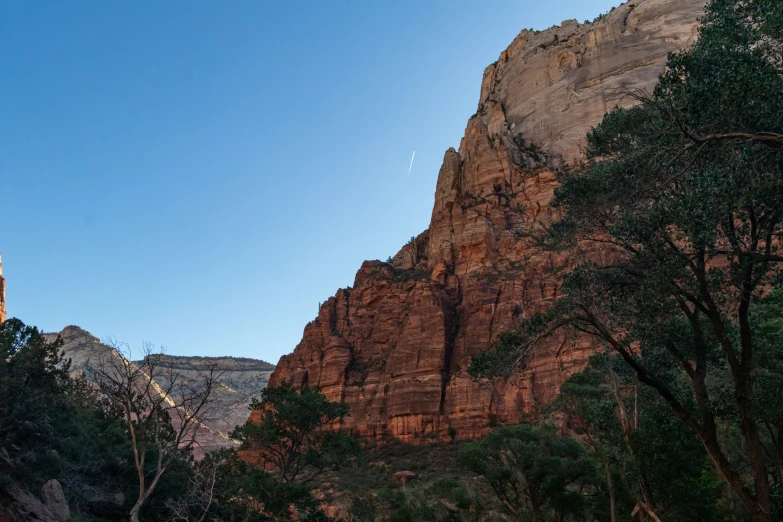 some tall rocks trees and mountains against a blue sky