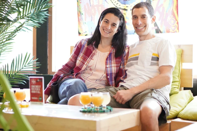 two people sitting on top of a couch near a window