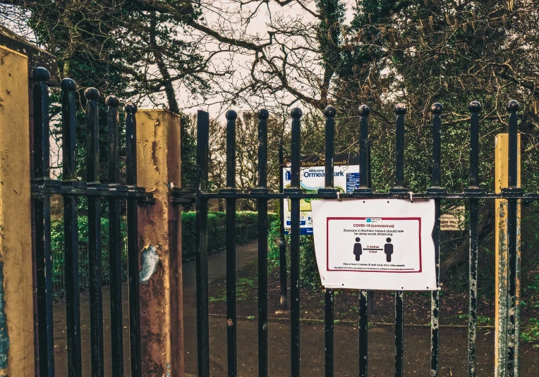 an informational sign and fence near some trees