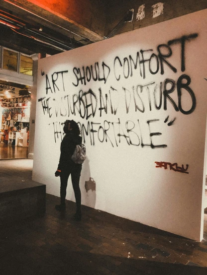 a woman is standing next to a large wall with words written all over it