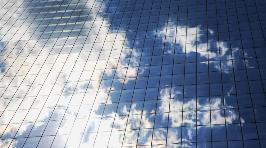 the side of a building with some clouds reflecting off of it