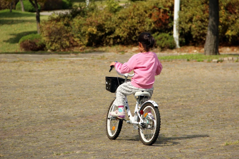 a little girl riding on the back of a white bicycle