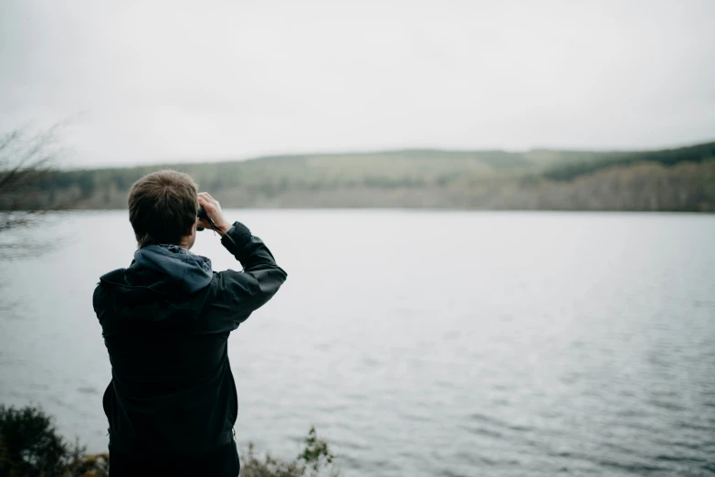 a person stands near the water, observing