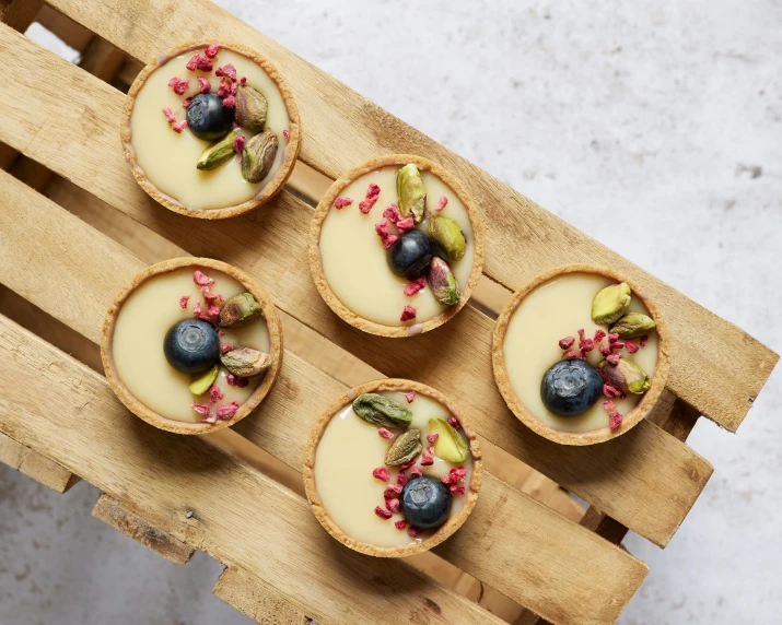 four cheese cakes topped with blueberries and flowers