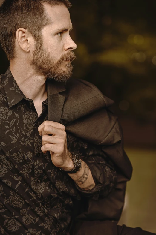 a bearded man holding onto a black jacket