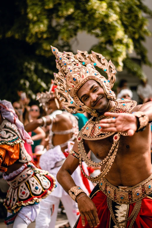 a man wearing an ornately adorned headpiece dances in a parade